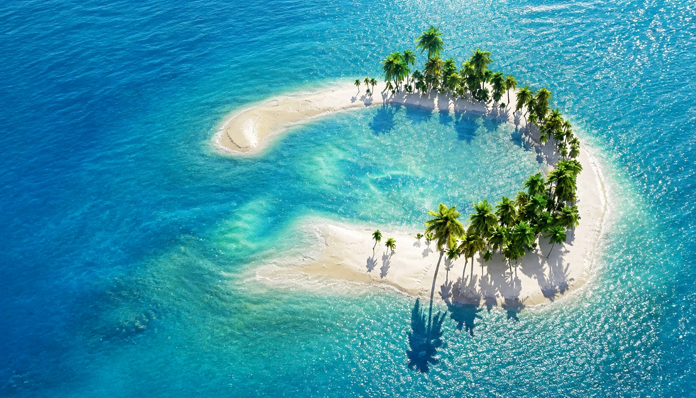 Aerial view of a small palm island in turquoise water
